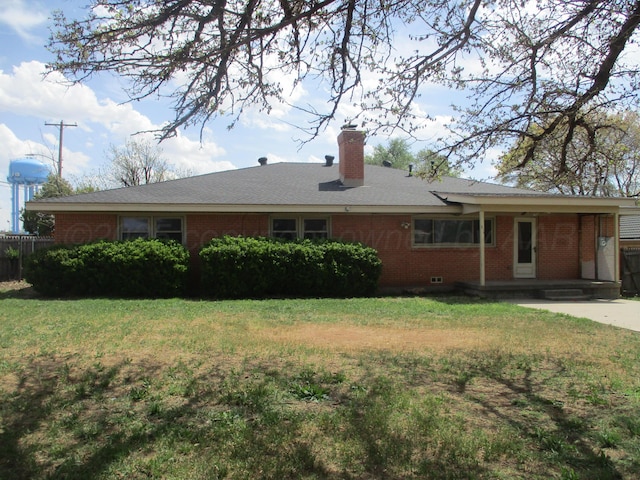 rear view of house with brick siding, a lawn, and a chimney