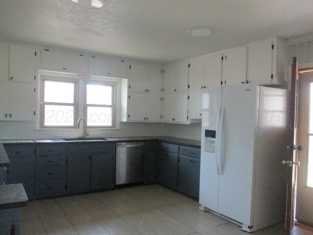 kitchen featuring white refrigerator with ice dispenser, stainless steel dishwasher, a sink, and plenty of natural light