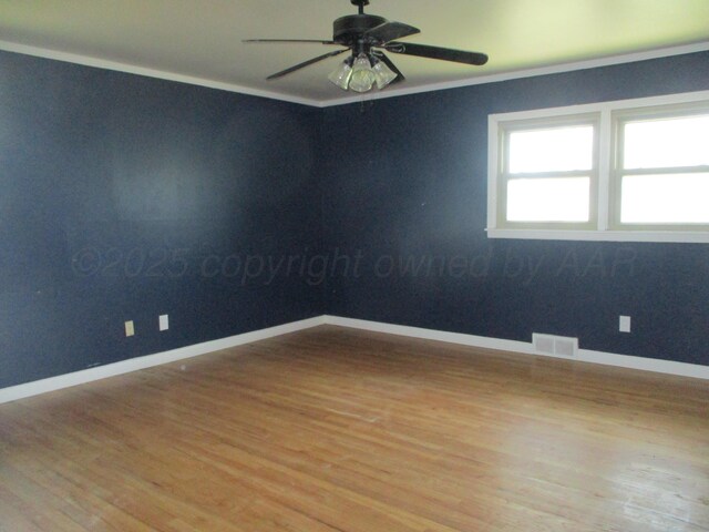 empty room with wood finished floors, crown molding, baseboards, and a ceiling fan