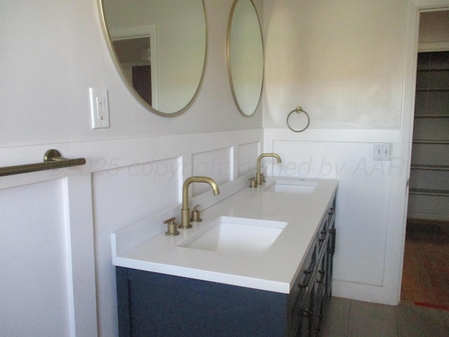full bathroom with double vanity and a wainscoted wall