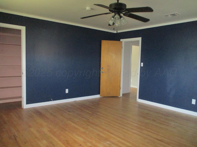 spare room with ceiling fan, wood finished floors, baseboards, crown molding, and a smoke detector