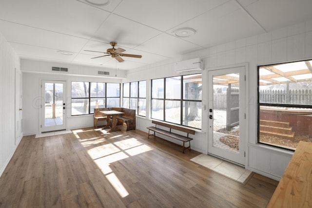 unfurnished sunroom with an AC wall unit and ceiling fan