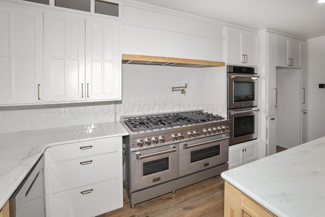 kitchen with white cabinetry, high end appliances, and hardwood / wood-style floors