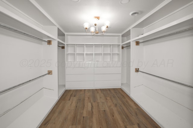 spacious closet with dark wood-type flooring and a chandelier