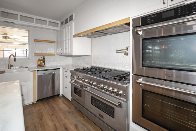 kitchen with appliances with stainless steel finishes, dark wood-type flooring, sink, and white cabinets