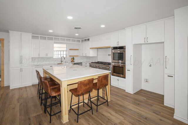 kitchen with stainless steel appliances, a kitchen breakfast bar, white cabinets, and a kitchen island