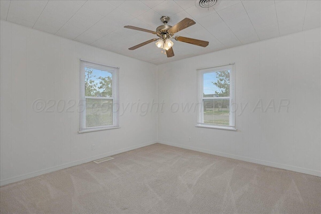 unfurnished room with light colored carpet, visible vents, a ceiling fan, and a healthy amount of sunlight