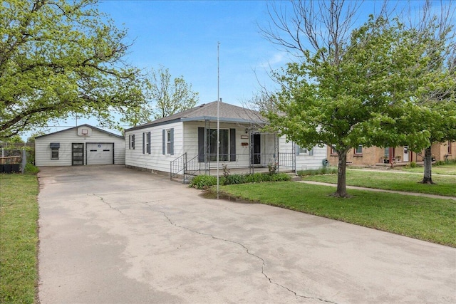 view of front facade featuring covered porch, a garage, concrete driveway, a front yard, and an outbuilding