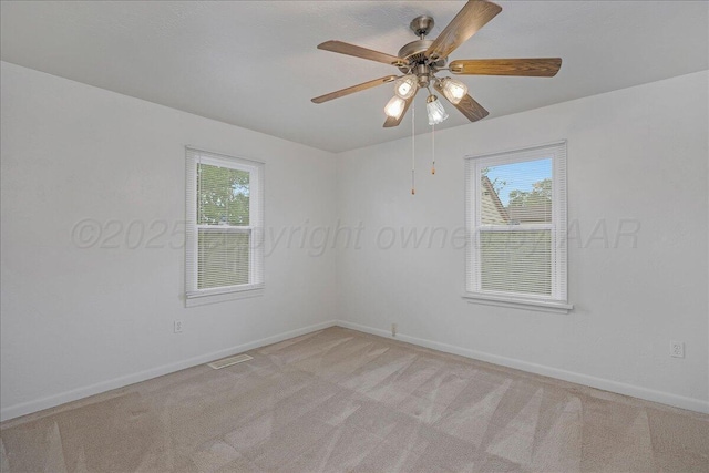 empty room with light carpet, baseboards, a ceiling fan, and visible vents