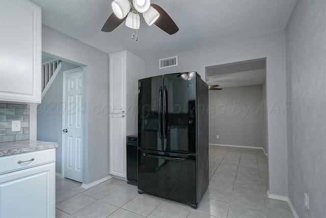 kitchen with black refrigerator, decorative backsplash, white cabinets, and ceiling fan