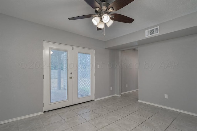 empty room with ceiling fan, light tile patterned flooring, and french doors