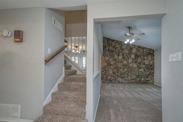 staircase featuring ceiling fan, carpet floors, and vaulted ceiling