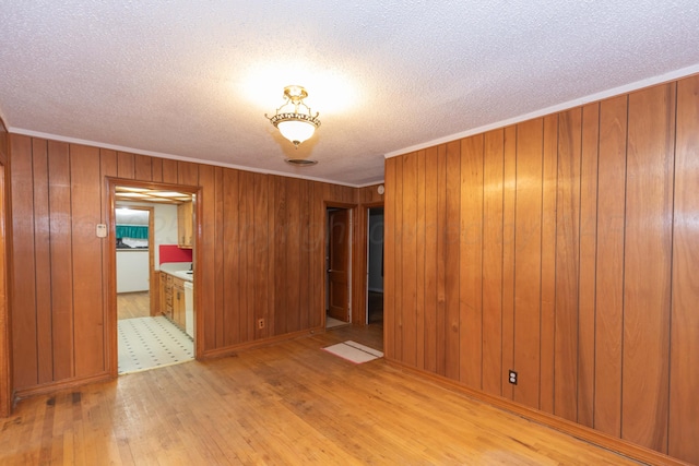 507 Aaron Rd, Fritch, TX 79036 - spare room with wood walls, crown molding, a textured ceiling, and light wood-style floors
