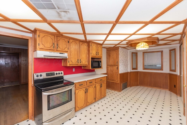 507 Aaron Rd, Fritch, TX 79036 - kitchen featuring under cabinet range hood, brown cabinetry, stainless steel electric stove, black microwave, and a wainscoted wall