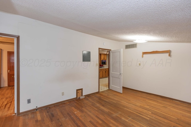 507 Aaron Rd, Fritch, TX 79036 - spare room featuring baseboards, electric panel, a textured ceiling, and wood finished floors