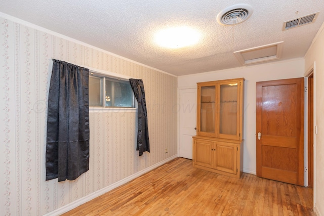 507 Aaron Rd, Fritch, TX 79036 - spare room with light wood finished floors, crown molding, a textured ceiling, and visible vents