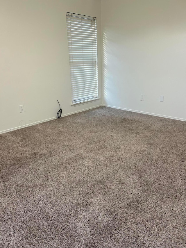 carpeted empty room with baseboards