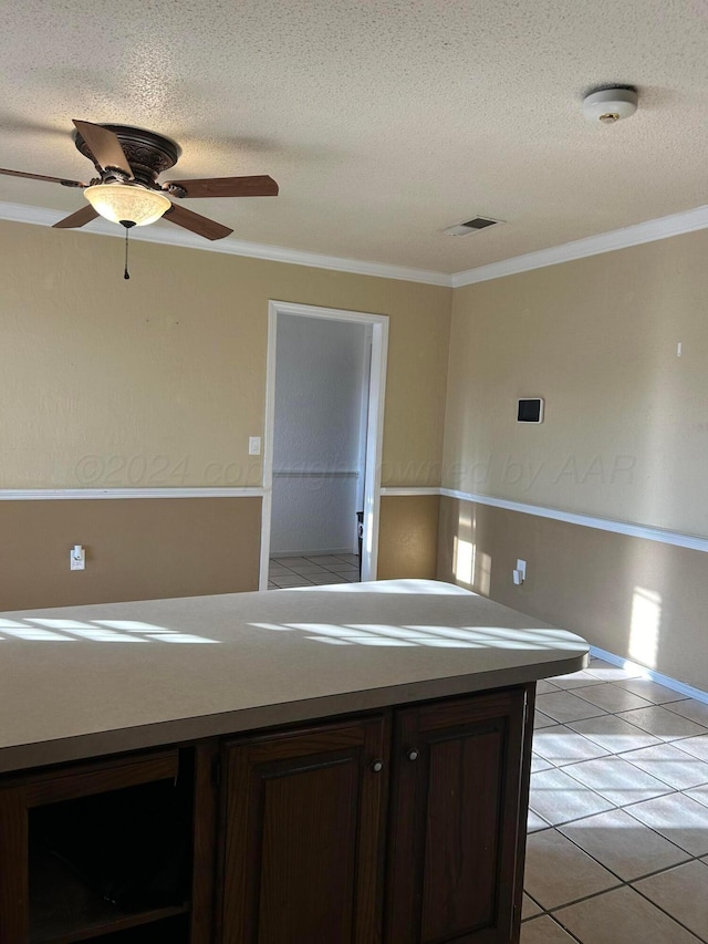 kitchen featuring visible vents, a textured ceiling, crown molding, light tile patterned floors, and dark brown cabinets