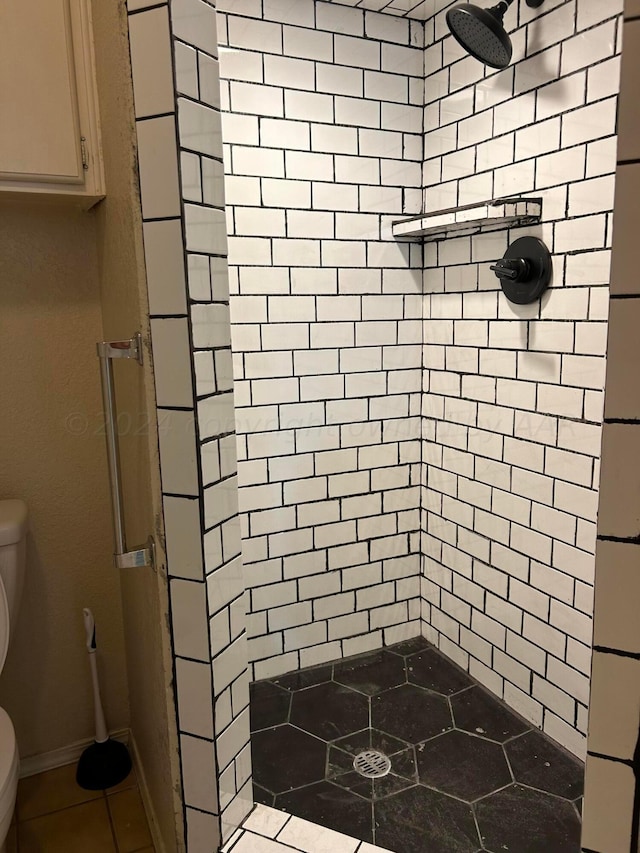 bathroom featuring tiled shower and toilet