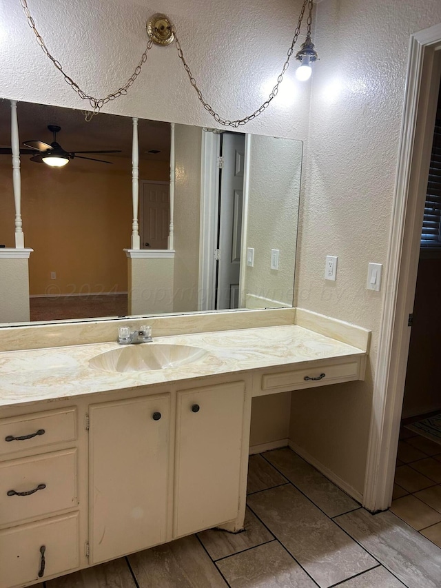 bathroom with tile patterned flooring, vanity, ceiling fan, and a textured wall