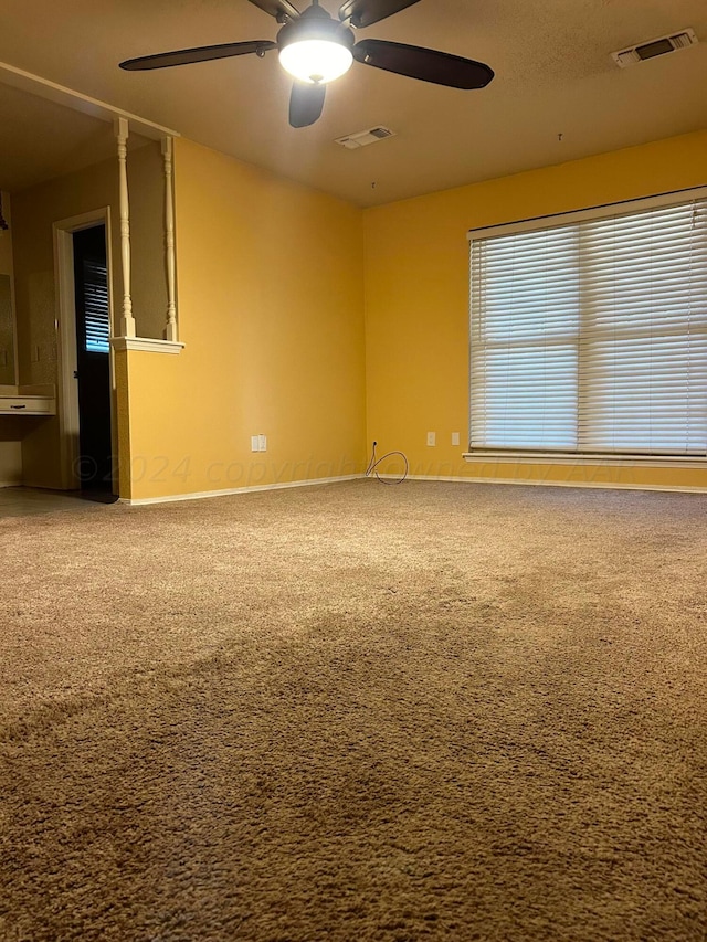 carpeted empty room with visible vents and ceiling fan