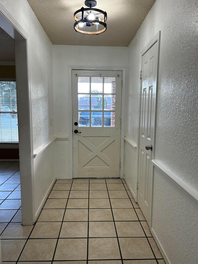 doorway with a textured ceiling, a healthy amount of sunlight, and a textured wall