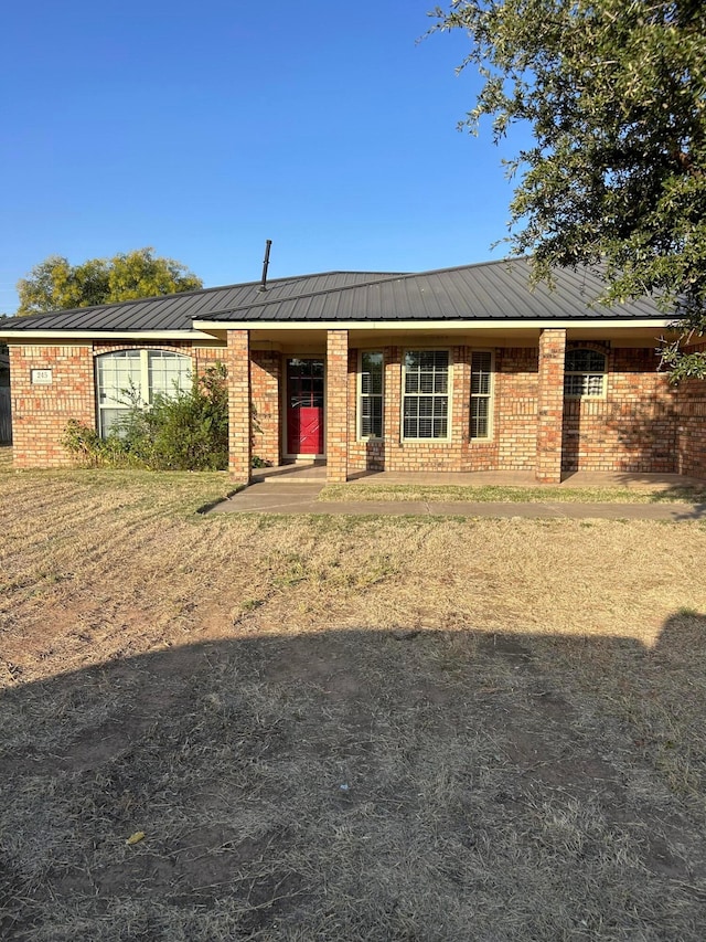 ranch-style house featuring brick siding and metal roof