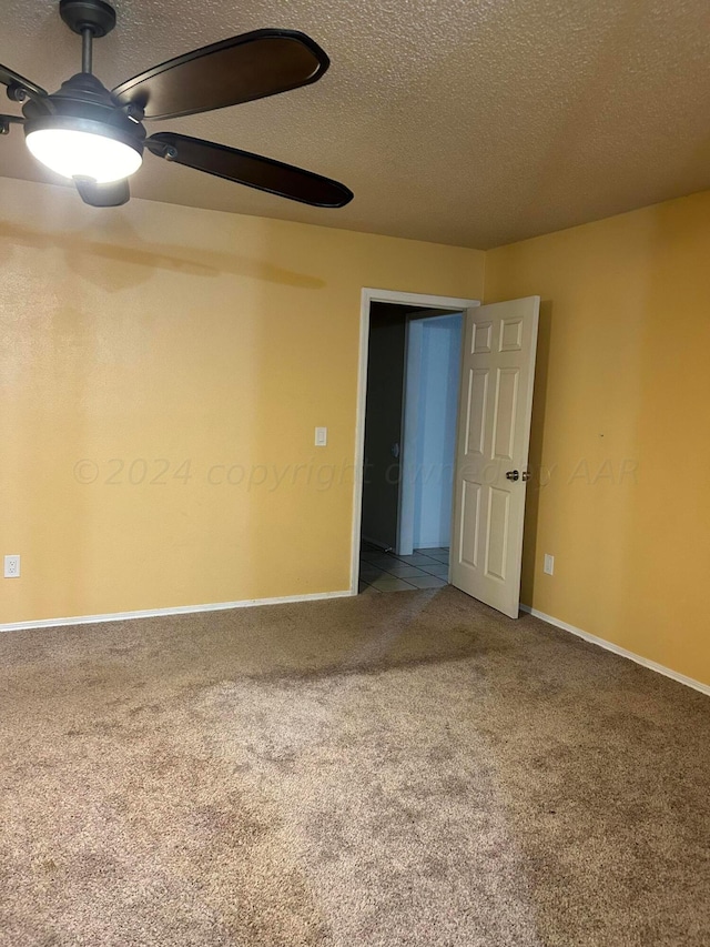 spare room featuring baseboards, a textured ceiling, and carpet flooring