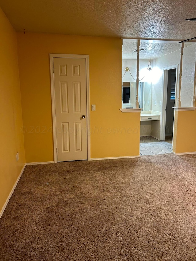 carpeted empty room with baseboards and a textured ceiling