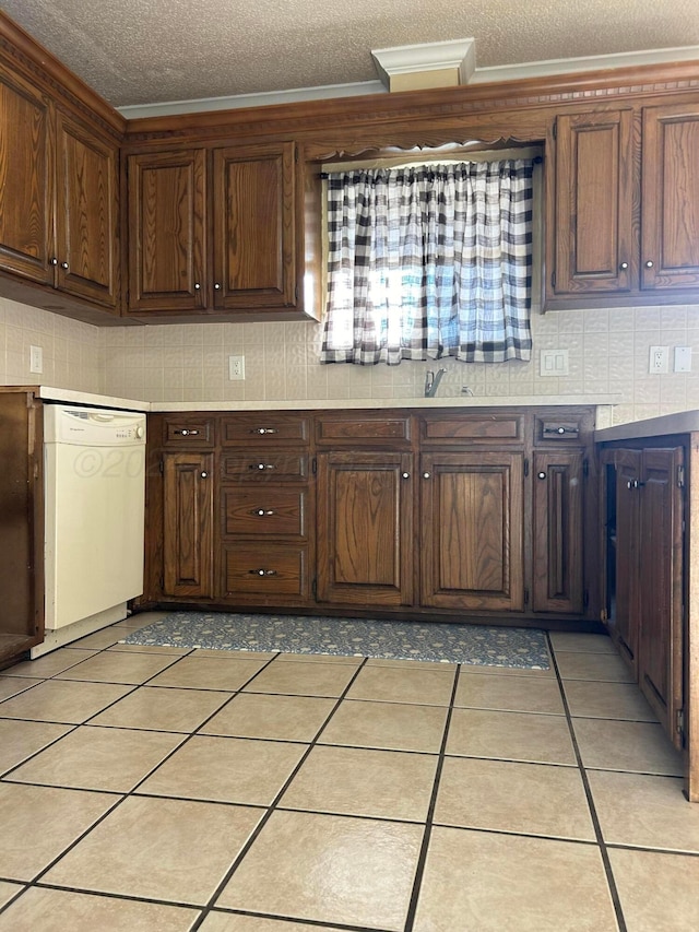 kitchen with light tile patterned floors, a textured ceiling, white dishwasher, and crown molding