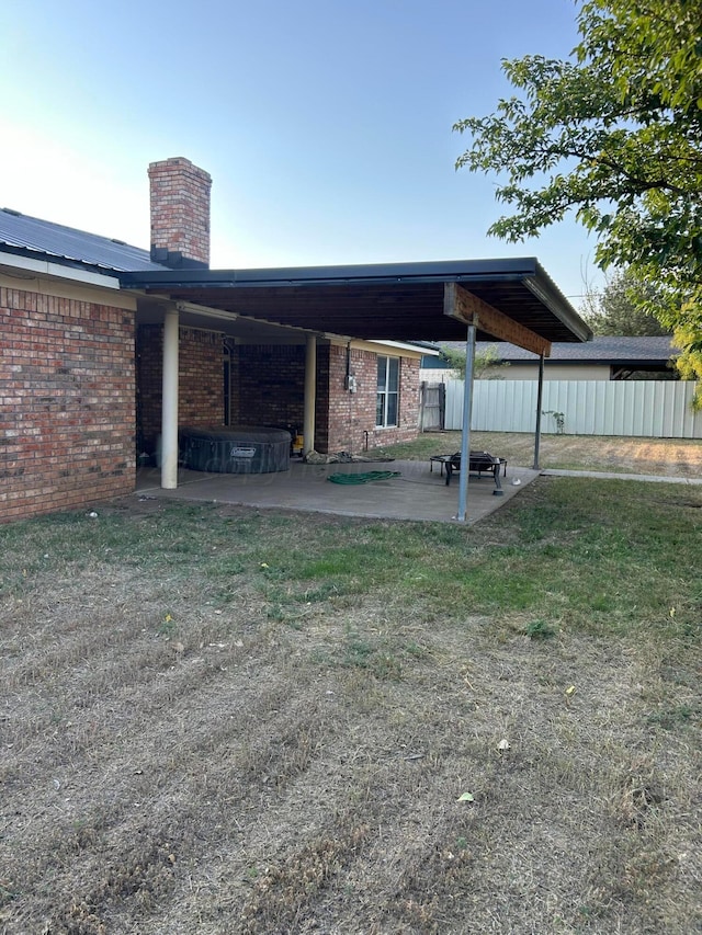 rear view of house with fence, a yard, a chimney, a patio area, and brick siding