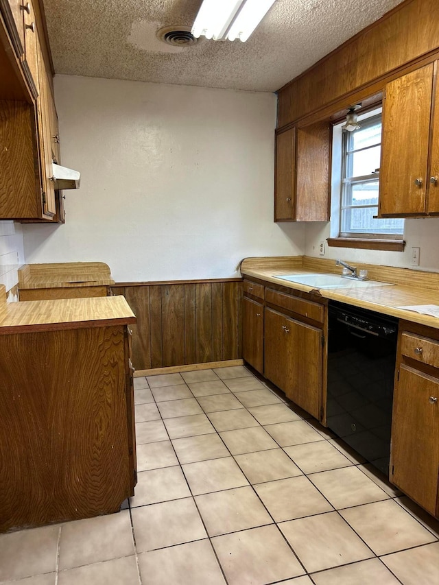 2914 Detroit St, Amarillo, TX 79103 - kitchen featuring black dishwasher, a textured ceiling, light countertops, wooden walls, and a wainscoted wall