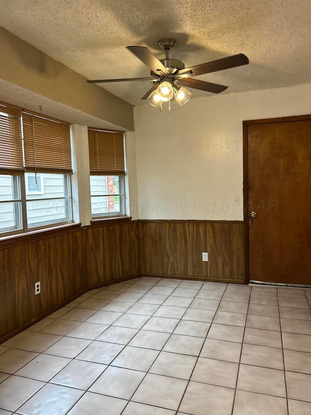 2914 Detroit St, Amarillo, TX 79103 - spare room with a textured ceiling, wood walls, a wainscoted wall, ceiling fan, and light tile patterned floors