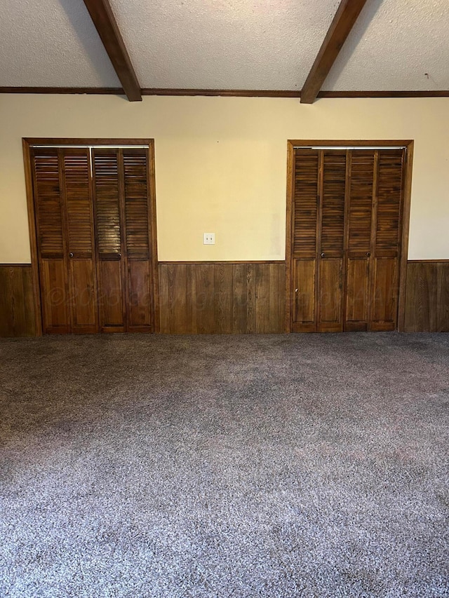 2914 Detroit St, Amarillo, TX 79103 - unfurnished bedroom with wainscoting, wooden walls, beam ceiling, a textured ceiling, and carpet