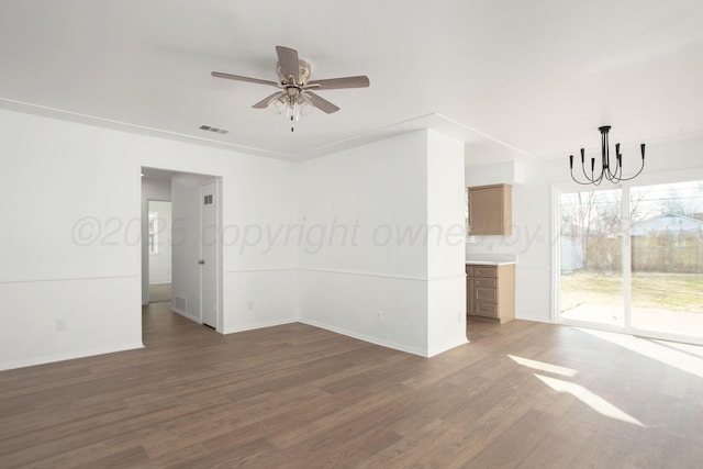 spare room with dark wood-type flooring and ceiling fan with notable chandelier