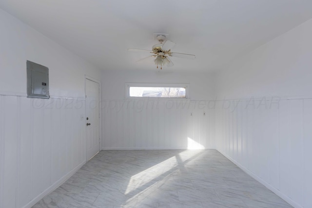 spare room with electric panel, ceiling fan, and wood walls