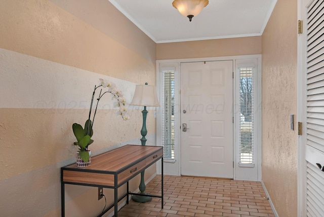 foyer with crown molding, a textured wall, brick patterned floor, and a wealth of natural light