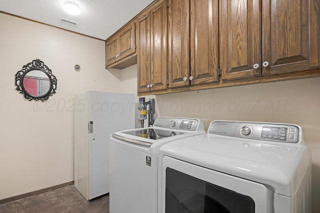 clothes washing area with a textured ceiling, visible vents, cabinet space, and washer and dryer