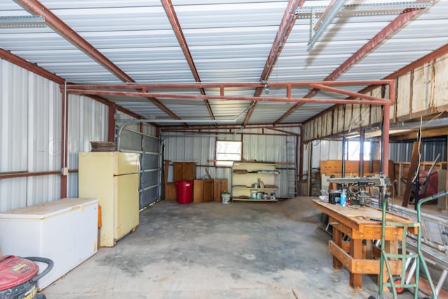 233 Doucette Dr, Howardwick, TX 79226 - garage with freestanding refrigerator, metal wall, and a workshop area