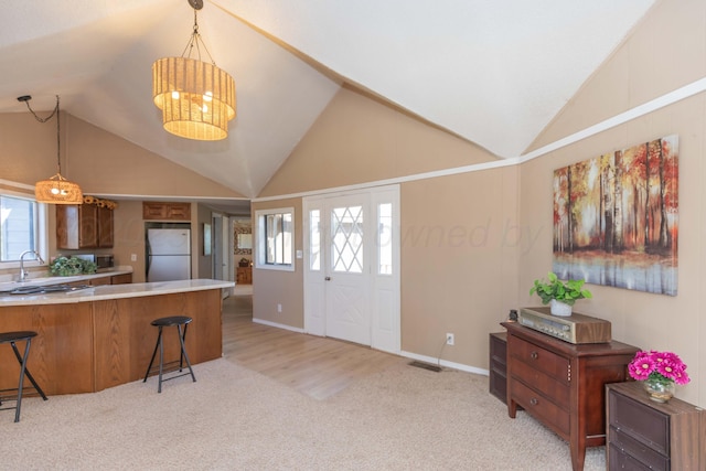 233 Doucette Dr, Howardwick, TX 79226 - kitchen featuring freestanding refrigerator, a breakfast bar, light carpet, light countertops, and high vaulted ceiling