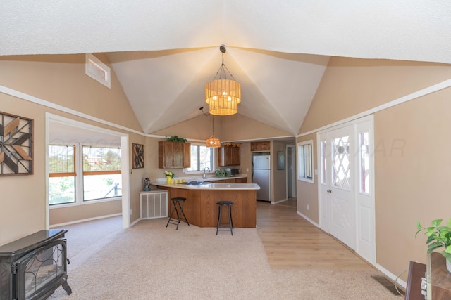 233 Doucette Dr, Howardwick, TX 79226 - kitchen with freestanding refrigerator, light colored carpet, a peninsula, a wood stove, and vaulted ceiling