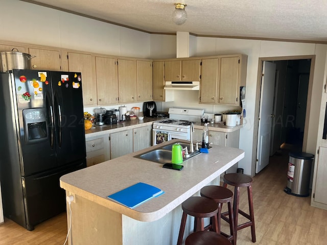 kitchen featuring vaulted ceiling, black fridge with ice dispenser, white gas stove, and a kitchen island with sink