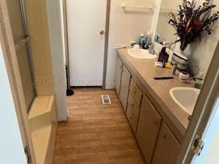 bathroom featuring hardwood / wood-style flooring, vanity, and an enclosed shower