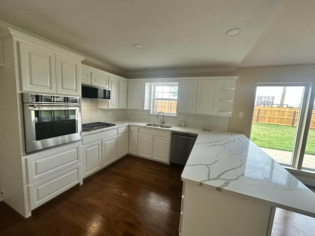 107 Galahad St, Borger, TX 79007 - kitchen featuring appliances with stainless steel finishes, a sink, a peninsula, backsplash, and white cabinets