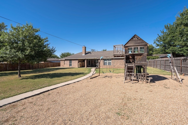 back of property with a playground, a lawn, a fenced backyard, and a chimney