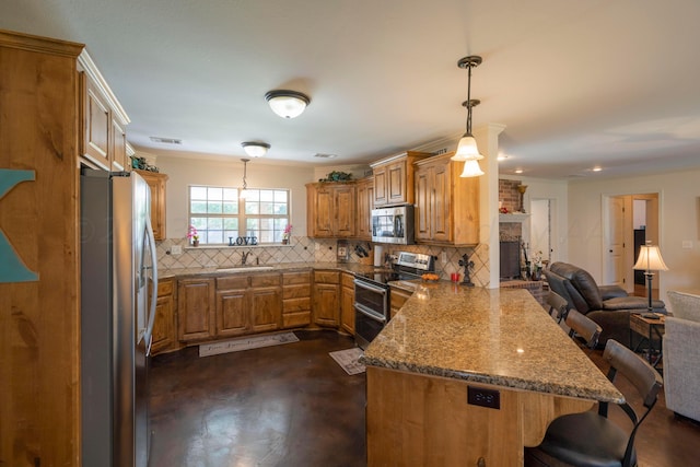 kitchen featuring open floor plan, a breakfast bar, appliances with stainless steel finishes, a peninsula, and a sink