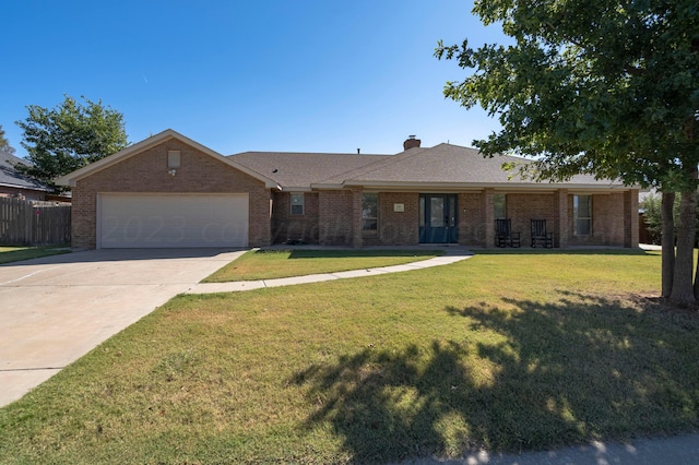 ranch-style home featuring a front yard, driveway, a chimney, a garage, and brick siding