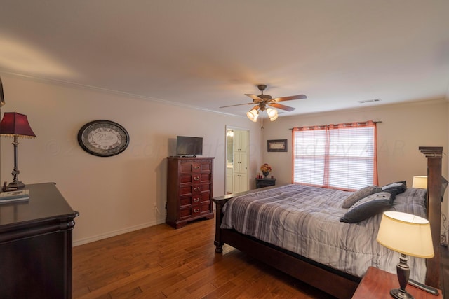 bedroom with visible vents, crown molding, baseboards, and wood finished floors