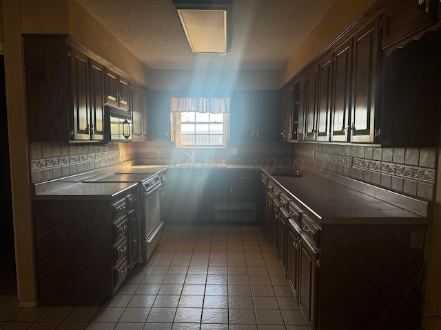 801 Skyline Dr, Borger, TX 79007 - kitchen with range with electric cooktop, black microwave, a textured ceiling, light tile patterned floors, and dark brown cabinets