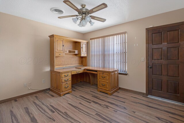 6814 Blacksmith Ln, Amarillo, TX 79109 - unfurnished office featuring wood finished floors, ceiling fan, built in desk, and a textured ceiling